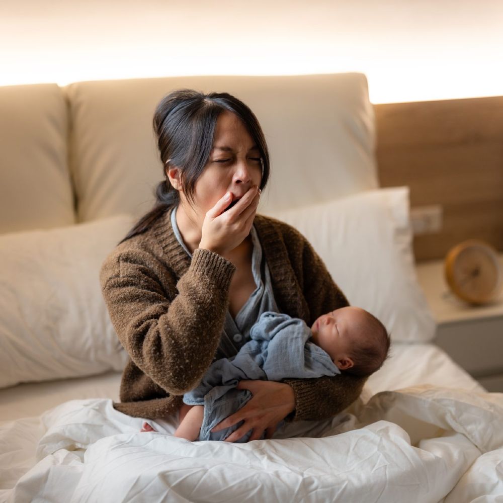 Tired new mom holding her sleeping newborn at night - whole-family postpartum support in the Hudson Valley